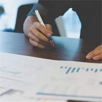 Bild på person med utskrivna papper framför sig med olika typer av grafer och diagram.