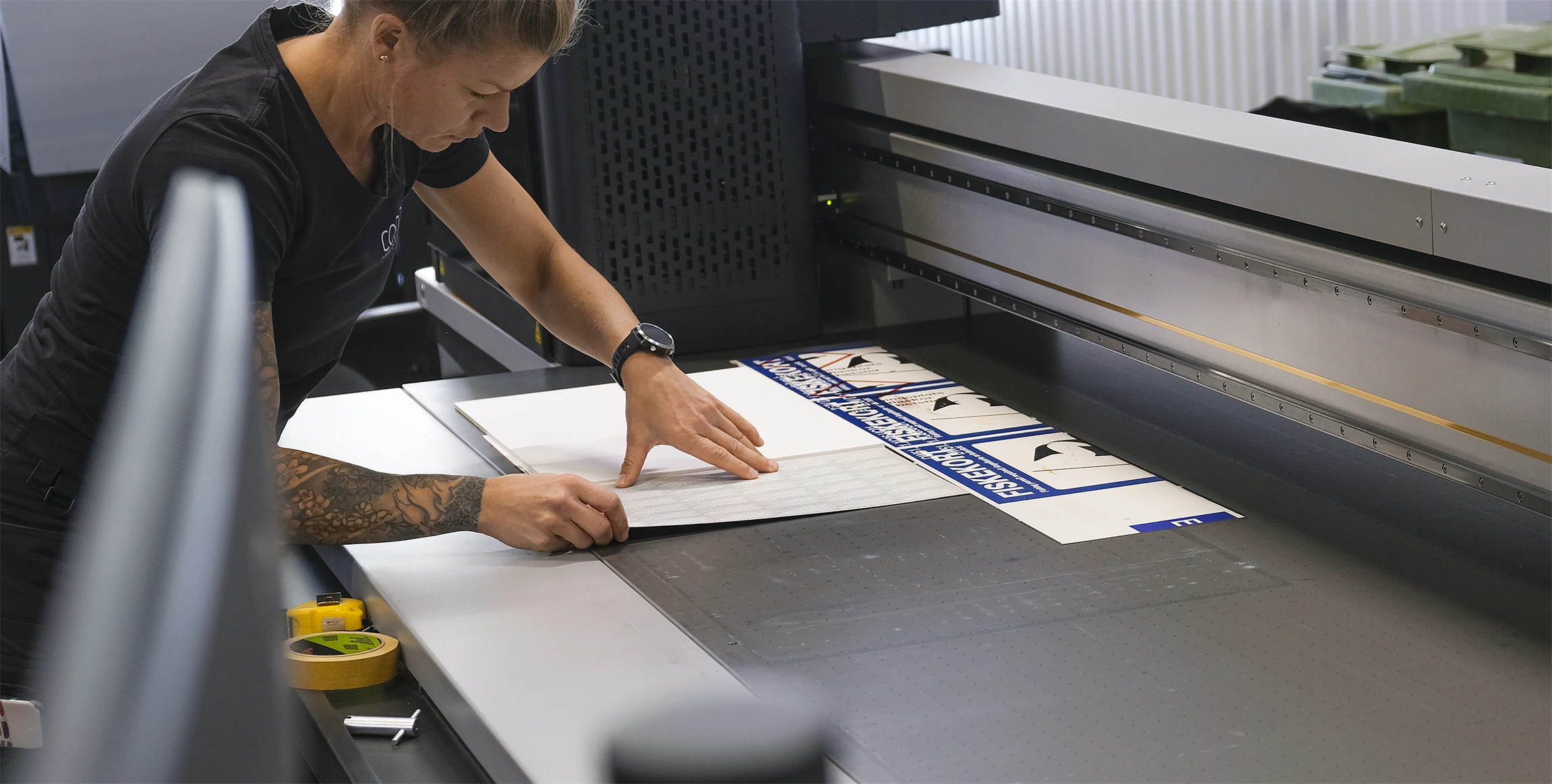 Bild på Skyltmakaren Sara Arvén som förbereder en produktion i en av Concils planprintrar. Bordet har ett antal olika vakuumzoner som stabiliserar skyltämnet.