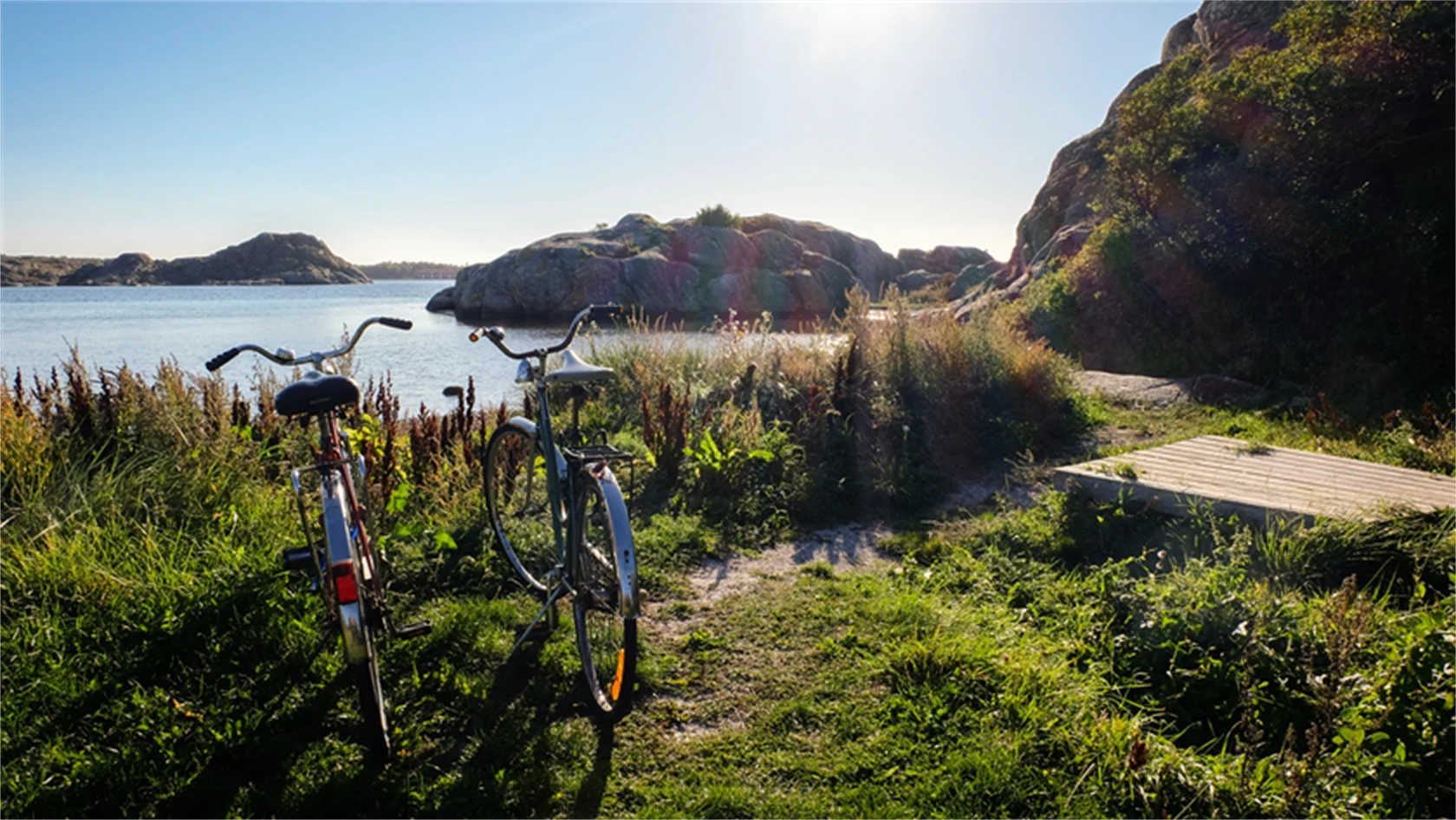 Somrig bild på två cyklar i skärgårdsmiljö.